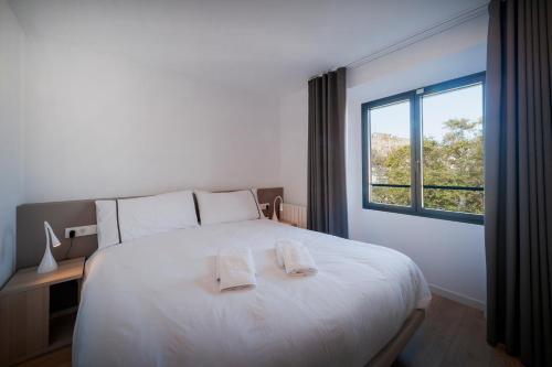 菲格拉斯NC Apartments Rambla 32的卧室配有一张白色大床和两条毛巾