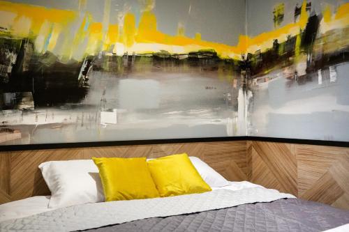 卢布林iroom的一张带黄色枕头的床和墙上的绘画