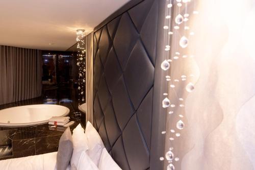 巴西利亚Cancún Hotel by H Hotéis - Airport的卧室配有大型黑色床头板和浴缸