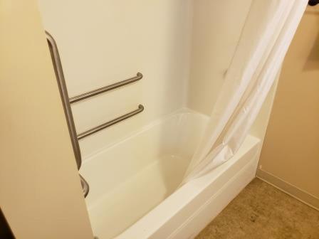 威利斯顿Clarion Hotel & Suites Near Pioneer Power Generating Station的浴室内设有带浴帘的白色浴缸