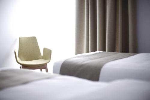贝尔格莱德BLEECKER Hotels的一间卧室设有两张床和一张靠窗的椅子
