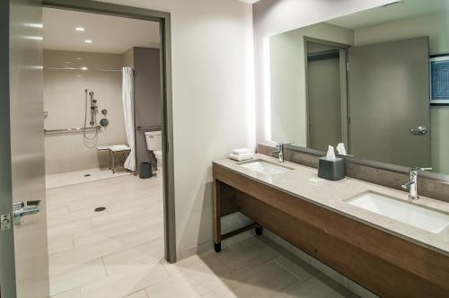 苏福尔斯Hyatt Place Sioux Falls South的一间带两个盥洗盆和淋浴的浴室