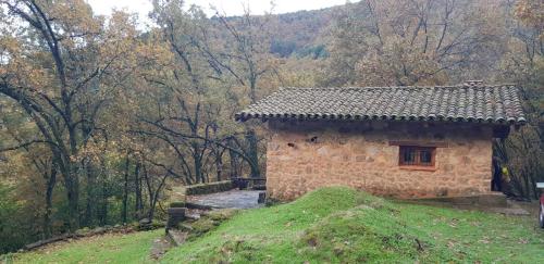 坎德莱达Cabaña Castañarejo的森林山丘上的一座小石头建筑