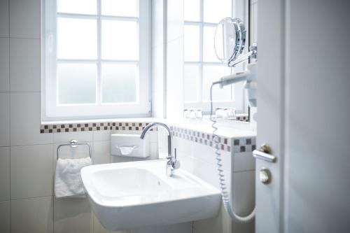 Wardenburg沃德伯格霍夫酒店的白色的浴室设有水槽和窗户。
