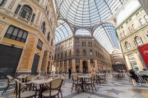 那不勒斯Royal Art H Duomo - Napoli Centro, by ClaPa Group的一座带桌椅和玻璃天花板的大型建筑