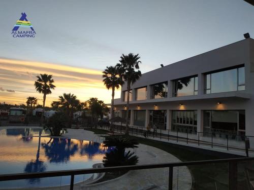 贝尼多姆阿尔马夫拉露营度假酒店的一座建筑,前面有游泳池和棕榈树