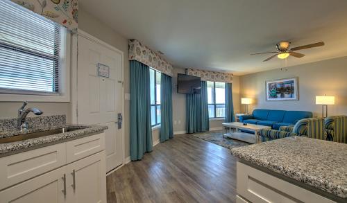 大西洋滩Atlantic Beach Resort, a Ramada by Wyndham的厨房以及带蓝色沙发的客厅。