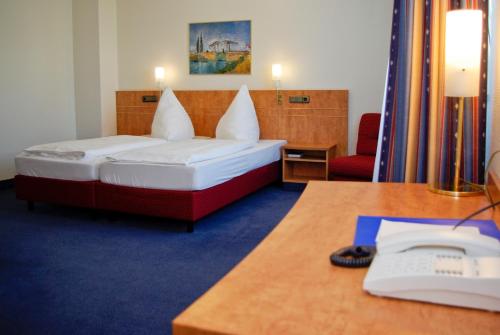 科隆科隆机场商业酒店的酒店客房配有一张床、一张书桌和电话