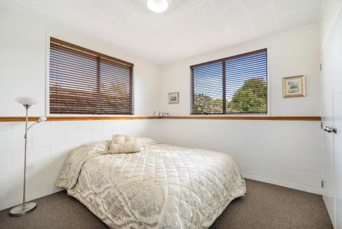KumeuKumeu Kottage的一间卧室设有一张床和两个窗户。