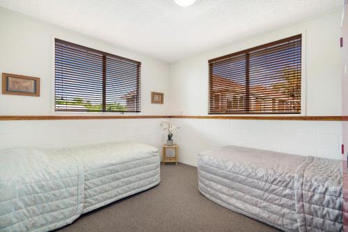 KumeuKumeu Kottage的一间卧室设有两张床和两个窗户。