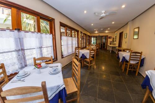 坎布里Pousada Azul Banana - Camburi的餐厅设有白色的桌椅和窗户。