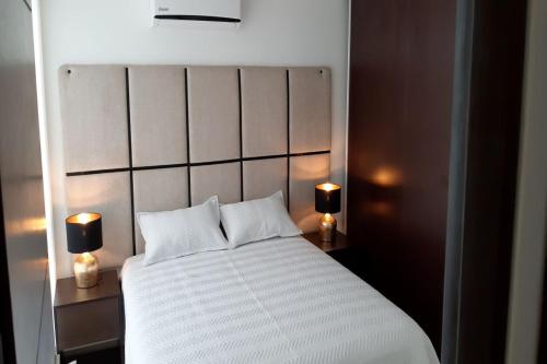 圣克鲁斯Elegante apartamento en Condominio Baruc II的一间卧室配有一张带两盏灯的大型白色床。