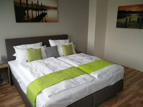 丁斯拉肯丁斯拉肯艺术酒店的一张大床,配有绿色和白色的床单