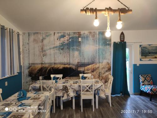 茹里洛夫卡Blue Bungalow Jurilovca的一间设有白色桌子和墙上绘画的用餐室
