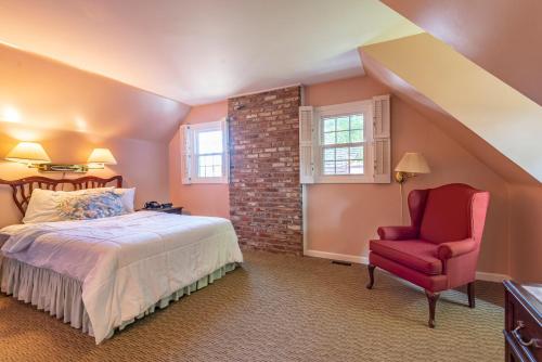 布卢明顿世纪套房酒店的一间卧室配有一张床和一张红色椅子