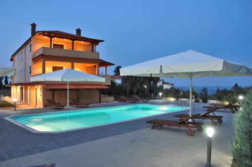 Achladi阿池拉迪海滩公寓式酒店的一个带两把遮阳伞和房子的游泳池
