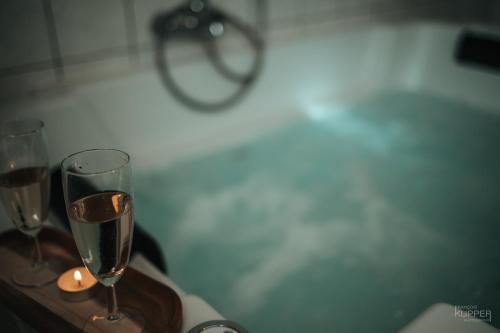 马尔梅迪Le Milan Royal 26 pers, Malmedy, Balnéo, vue, calme的浴缸内的木托盘上放两杯香槟
