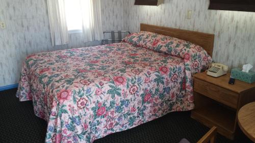 李城日落汽车旅馆的一间卧室配有一张带花卉床罩的床