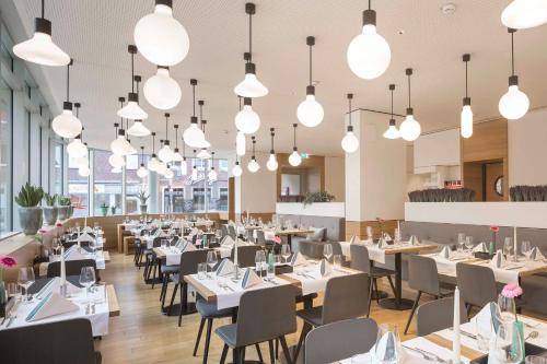 明斯特明斯特城市酒店的餐厅配有白色的桌椅和灯光