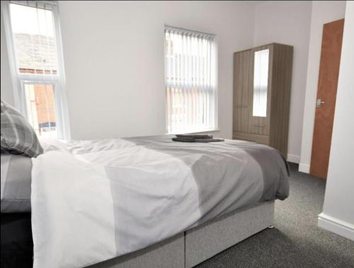 特伦特河畔斯托克Townhouse @ Birks Street Stoke的一间白色卧室,配有床和2个窗户