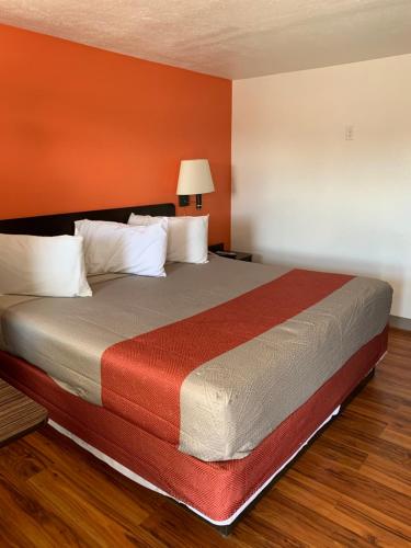 博登镇Scottish Inns and Suites- Bordentown, NJ的橙色墙壁的客房内的一张大床