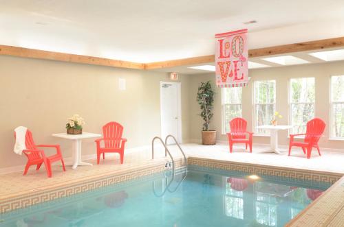 以法莲鹰港宾馆的一个带红色椅子和桌子以及桌椅的游泳池