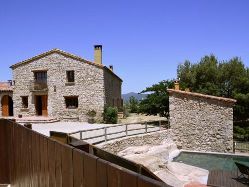CastellolíBelvilla by OYO Cal Sant Miquel的一座古老的石头房子,前面设有一个游泳池