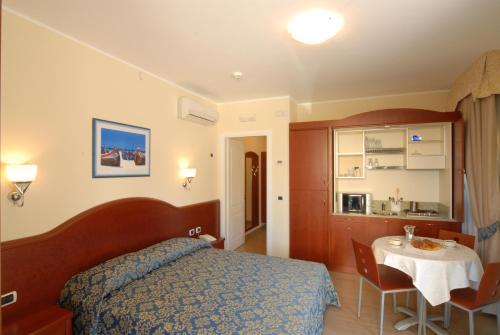 葛伦坦马勒Residence Costa Smeralda的一间卧室配有一张床铺和一张桌子,还设有一间厨房