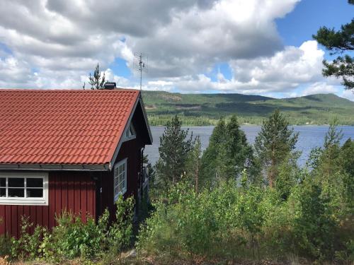 GunsjögårdenChalet in Torsby Municipality Middle with Sauna的湖边的红色房子,有红色屋顶