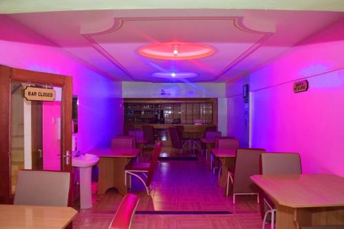 WundanyiTAITA LUXURY HOTELS LTD的餐厅内带桌椅的粉红色客房