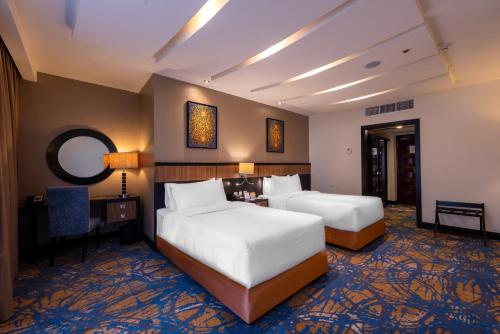 麦加Al Ghufran Safwah Hotel Makkah的酒店客房配有两张床和一张书桌