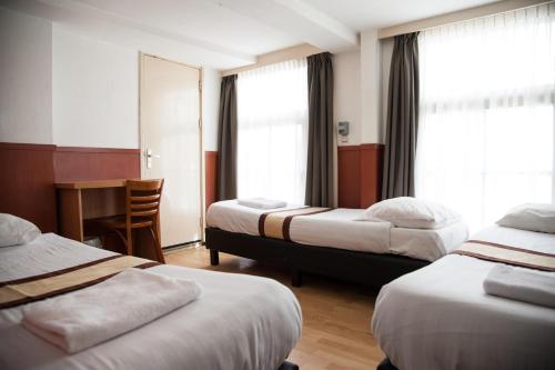 阿姆斯特丹Hotel Continental Amsterdam的酒店客房配有两张床和一张书桌