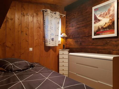 DomancyPetit chalet savoyard的卧室设有木墙、一张床和一个梳妆台