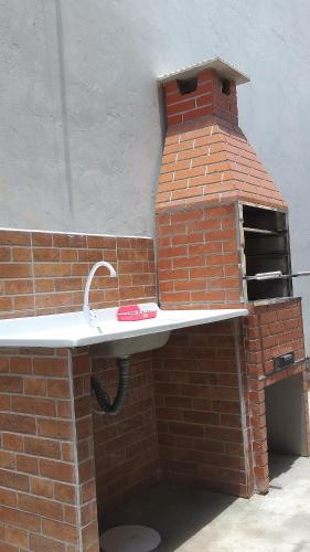 马蒂尼奥斯Residencial Chalés Riviera的砖墙内带水槽的砖炉