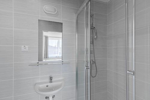 斯皮什新村Garni Hotel 31的白色的浴室设有水槽和淋浴。