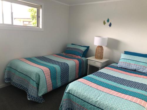 Whangarei HeadsTaurikura Bay Relax and Explore的一间卧室设有两张床和窗户。