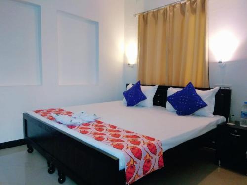 乌代浦Amritchandra homestay and hostel的一间卧室配有一张带蓝色和红色枕头的大床