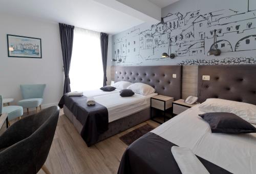 杜布罗夫尼克珀尔塔酒店的一间卧室设有两张床,墙上挂着画作。