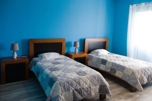 Feteira PequenaCasa dos cinco sentidos的一间卧室设有两张床和蓝色的墙壁