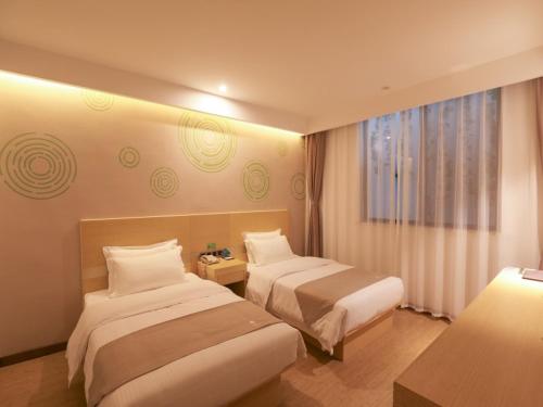 无锡格林豪泰无锡融创文旅城南泉镇商务酒店的酒店客房设有两张床和窗户。