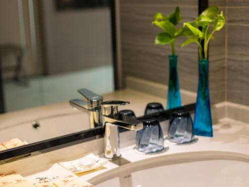 无锡格林东方无锡新区假日广场酒店的浴室水槽设有水龙头和镜子