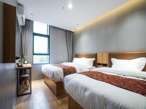上海Green Alliance Baoshan Shanghai University Qihua Road Metro Station的酒店客房设有两张床和窗户。