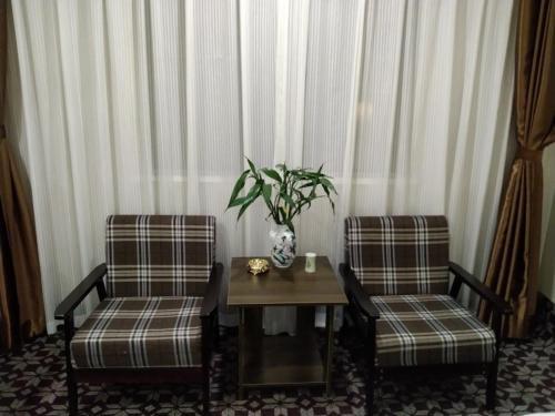 信阳格林联盟信阳平桥区南京路东阳酒店的两把椅子和一张桌子,上面有花瓶