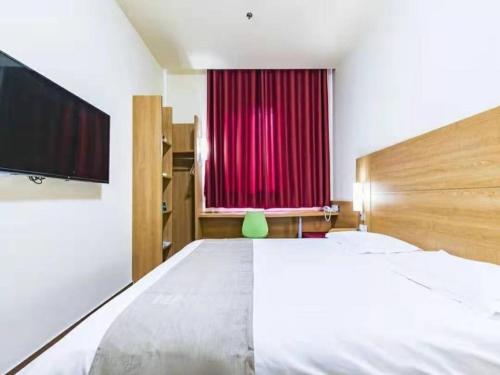 滨海新区格林豪泰天津市大港区石化路商务酒店的一间卧室配有一张大床和红色窗帘