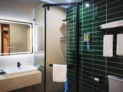 安顺格林豪泰黄果树瀑布景区智选酒店的绿色瓷砖浴室设有水槽和镜子