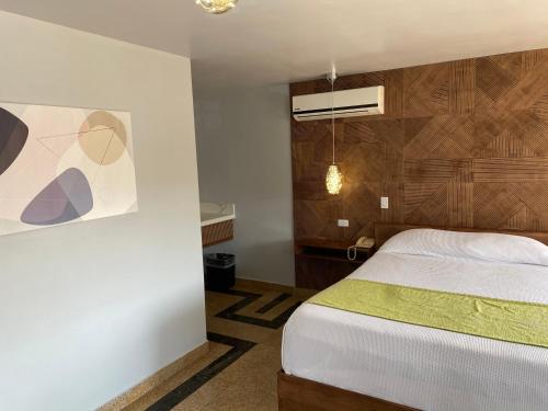 提华纳Hotel Aqua Rio的卧室配有一张床,墙上挂有绘画作品