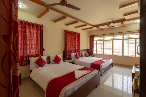 HalebīdKSTDC Hotel Mayura Shantala Halebeedu的配有红色窗帘的客房内的两张床