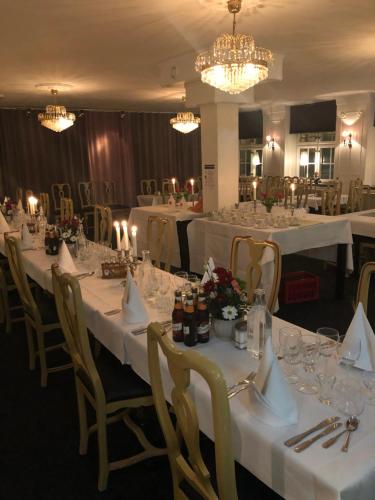 法尔肯贝里Värdshuset Hwitan的用餐室配有白色桌椅和吊灯。