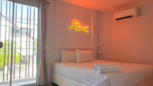 七岩七岩晚安迷你酒店的卧室配有一张墙上 ⁇ 虹灯标牌的床