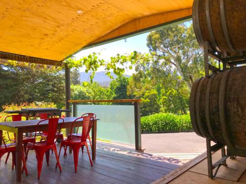 希尔斯维尔Valley Farm Vineyard Villas的庭院内木制甲板上配有桌子和红色椅子